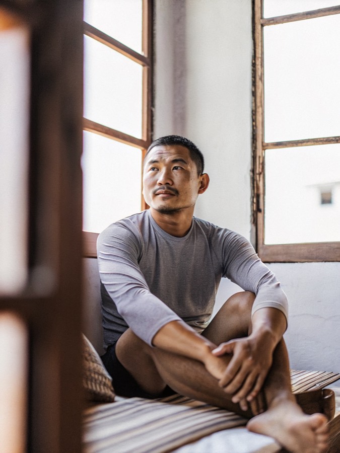 a Southeast Asian man in his early forties sitting in a daylit room after training